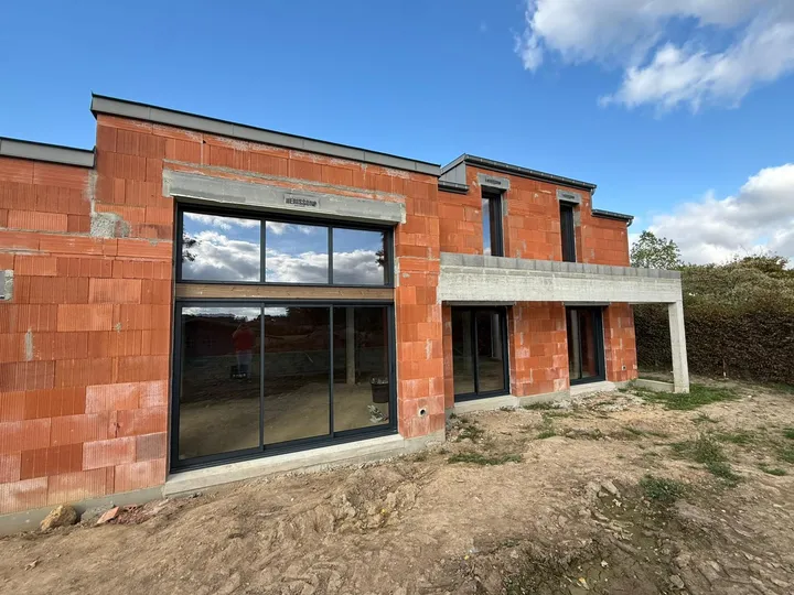 Ensemble vitré de grande hauteur sur la façade d’un bâtiment en brique en cours de construction