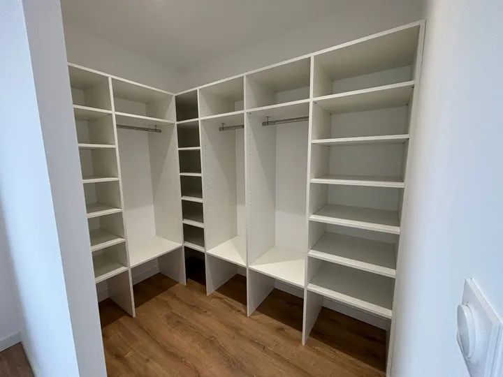 Dressing blanc en angle avec étagères et espaces de penderie