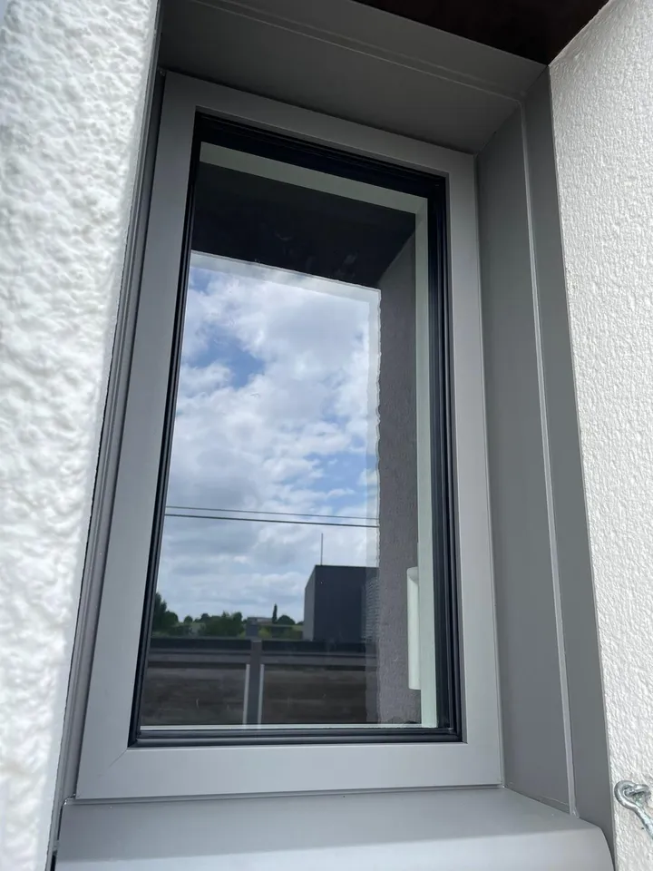 Fenêtre grise à un vantail dans un encadrement intérieur blanc