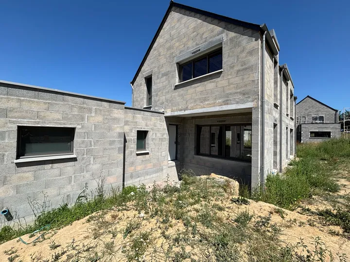 Fenêtres et grandes baies sombres sur les volumes d’une maison en cours de construction