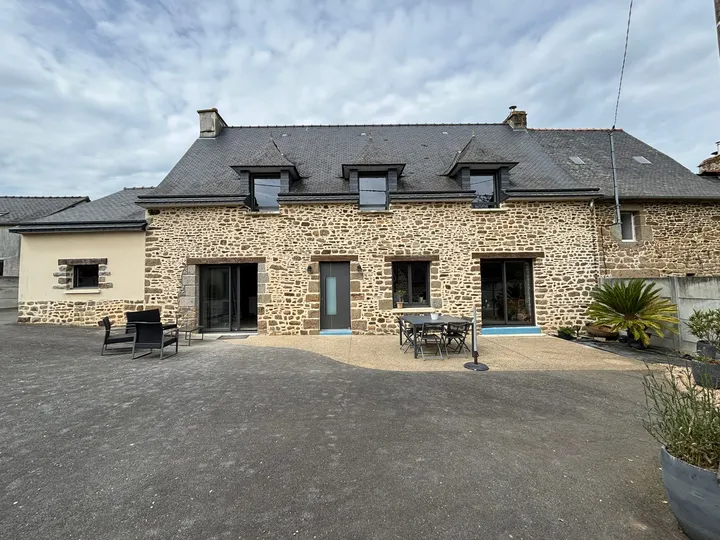 Baies et porte d’entrée sombres dans une maison en pierre à deux niveaux