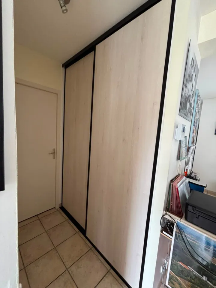 Façades coulissantes aspect bois avec cadres noirs dans une entrée carrelée