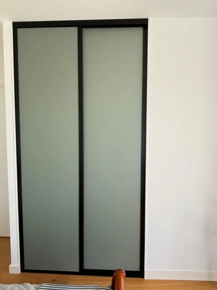 Deux façades de placard coulissantes vert doux dans des cadres noirs