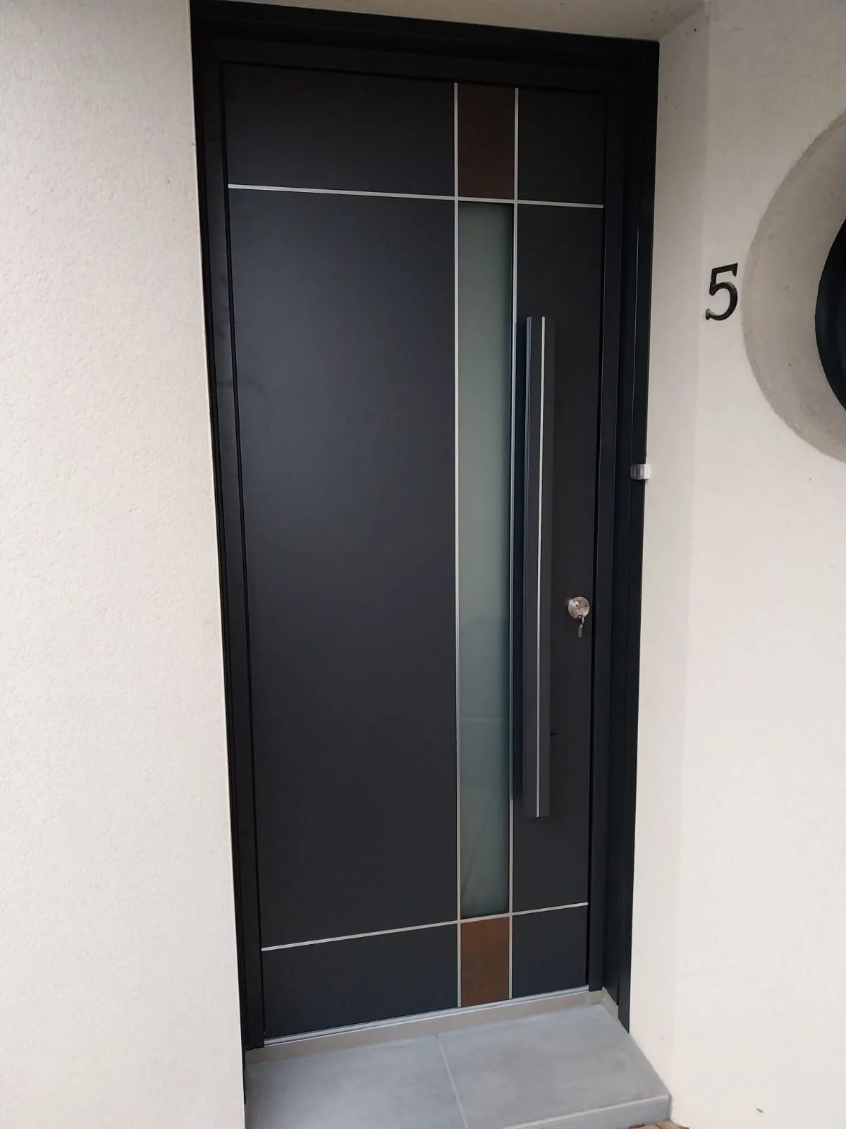 Porte d’entrée gris foncé avec inserts verticaux, posée à Gosné