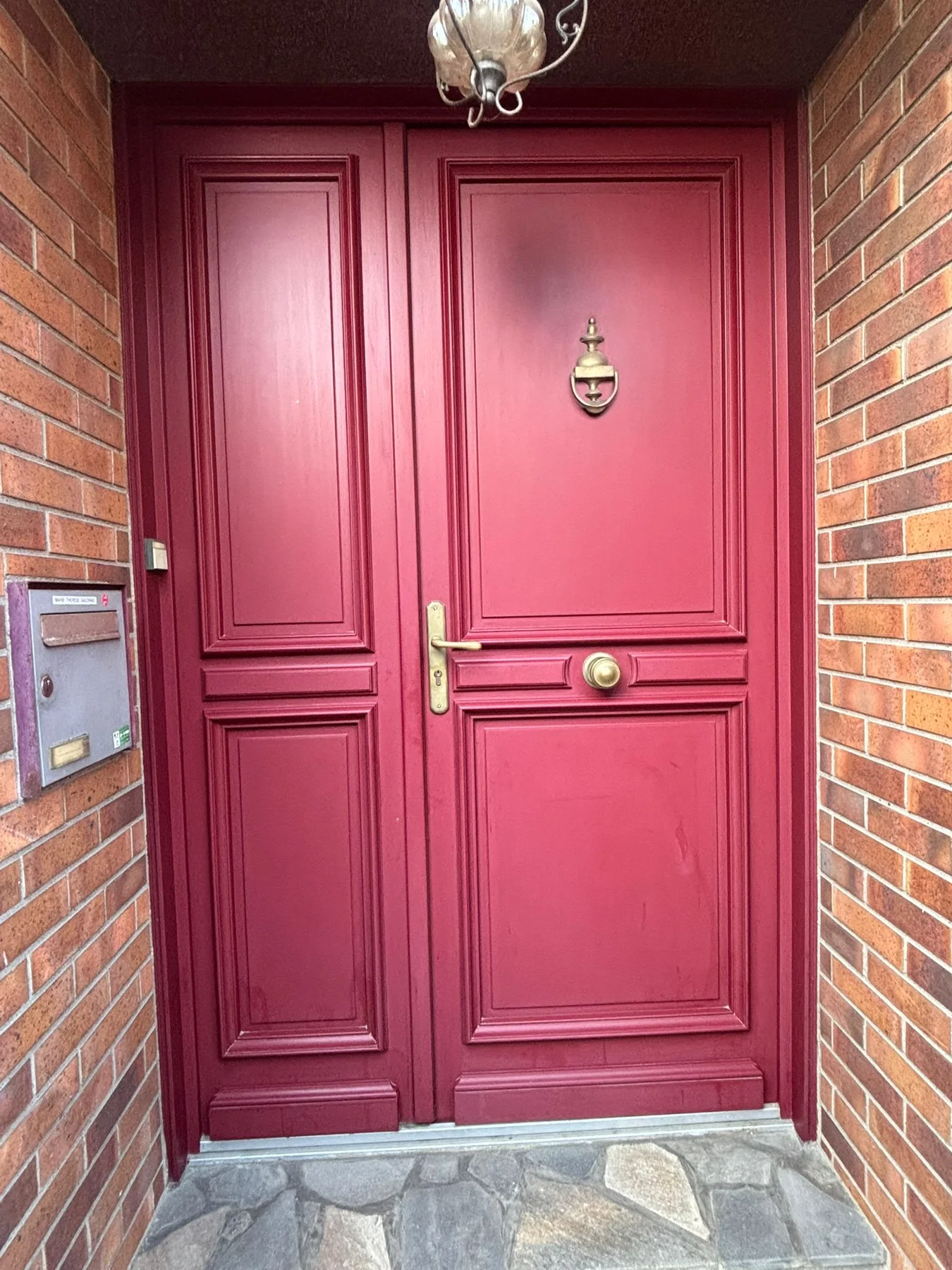 Ancienne porte d’entrée rouge à panneaux et petits vitrages