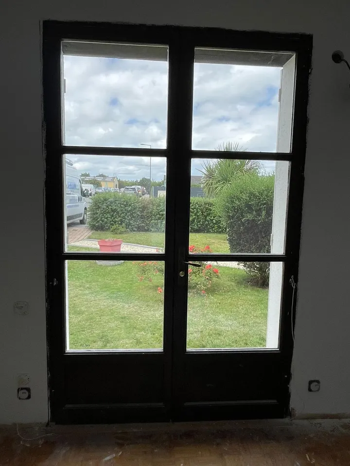 Porte-fenêtre noire à traverses horizontales, vue depuis l’intérieur