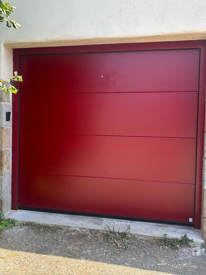 Porte de garage rouge à panneaux horizontaux dans une façade enduite