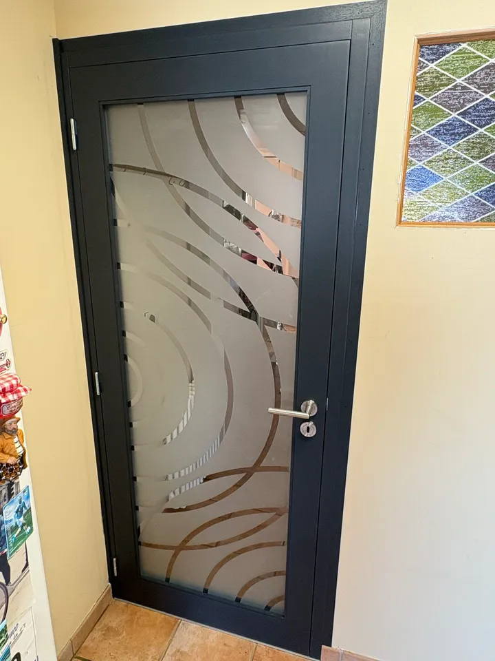 Porte intérieure à cadre sombre et vitrage décoré de lignes courbes