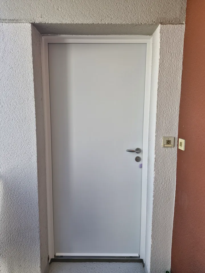 Porte palière blanche avec poignée et judas dans une entrée