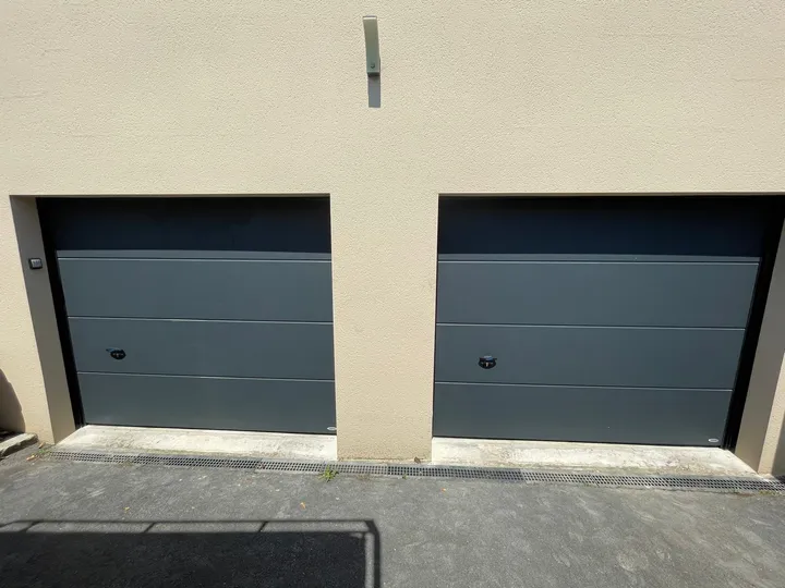 Deux portes de garage anthracite côte à côte dans une façade claire